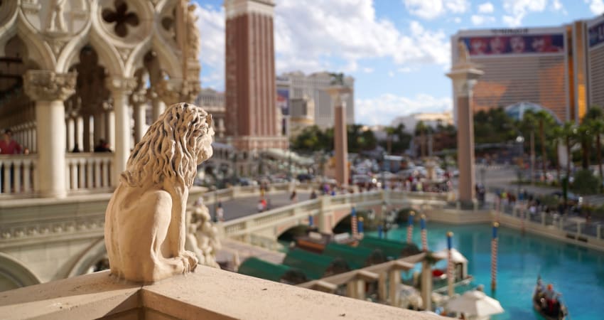 View from a balcony in the Caesar's Palace casino complex, with a sunny day and gondola canals visible in the background and a small gargoyle in the foreground