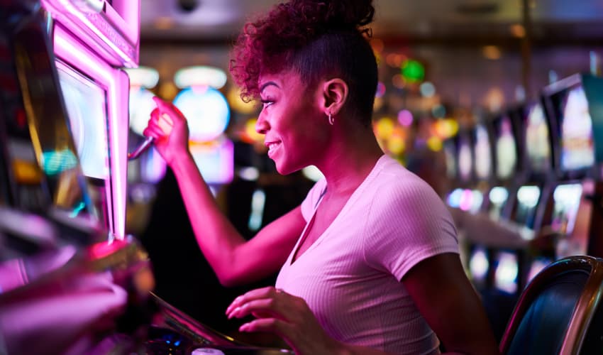 A woman plays a slot game in a dark casino