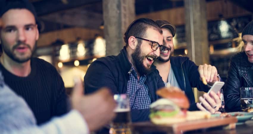 A group of friends laughing over burgers and beer at a bar
