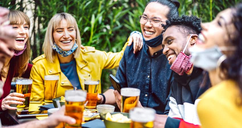 A group of friends laughing over beer on an outdoor patio