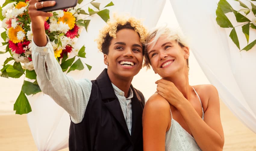 A happy lesbian couple smiles and takes a selfie on their wedding day