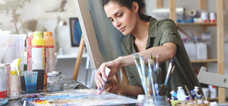 a woman squeezes paint onto a canvas