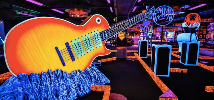 a large neon guitar sculpture under a glowing blacklight