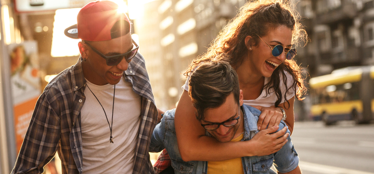 friends laugh and smile while they walk down the street at sunset