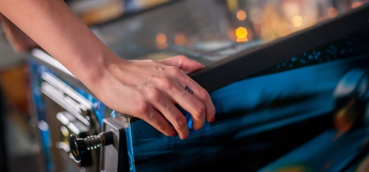 a hand rests on a pinball machine