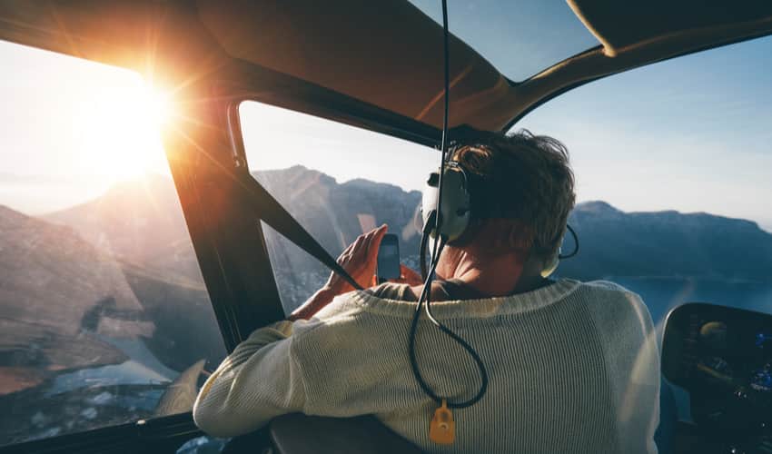 a passenger taking photos from a helicopter tour