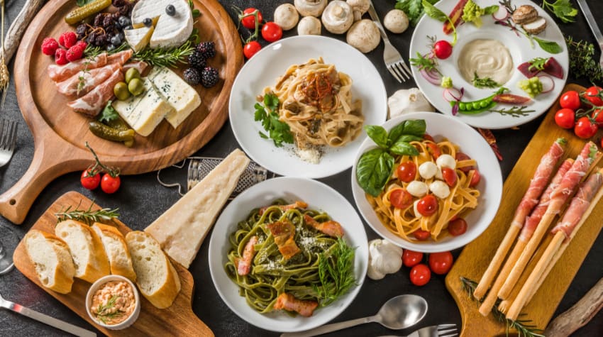 a spread of italian food with tomatoes, pasta, herbs, and other colorful foods