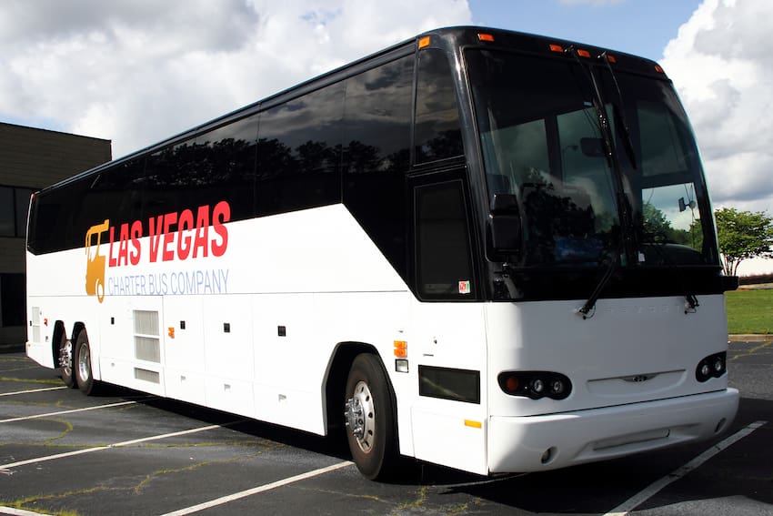 a plain white charter bus with the "las vegas charter bus company" logo on the side, parked on concrete