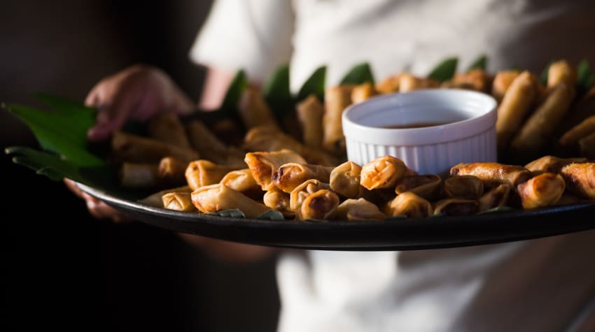 a waiter holds a plate filled with small h'ors d'oeuvres 