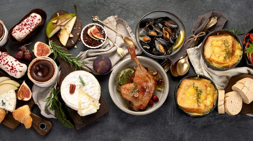 classic french food spread on a table including chicken, cheese, and herbs